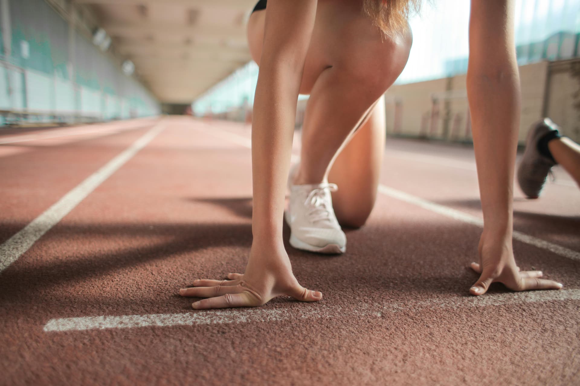 A runner crouches on an athletic track ready for a race